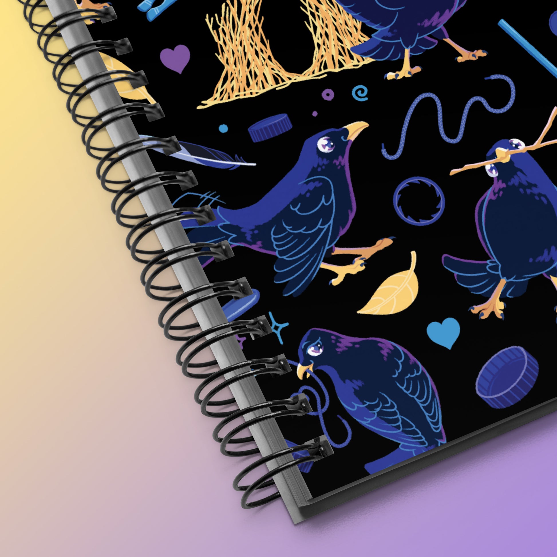 Close up of a spiral notebook with a colourful purple, blue and yellow satin bowerbird pattern on a yellow and purple gradient background.