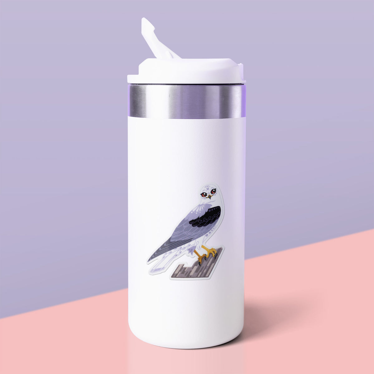 Colourful sticker of a black-shouldered kite perched on a branch stuck to a white metal drink bottle on a soft pink table on a lilac background.
