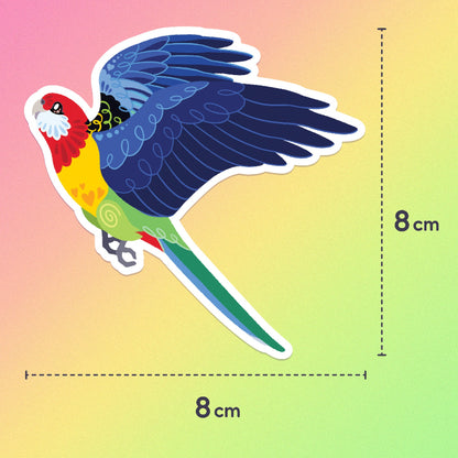 8x8cm colourful sticker of an Eastern Rosella in flight on a pink, orange, yellow and green gradient background.
