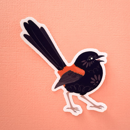 Real photo of a colourful sticker of a male Red-backed Fairywren chirping on a peach canvas texturedbackground.