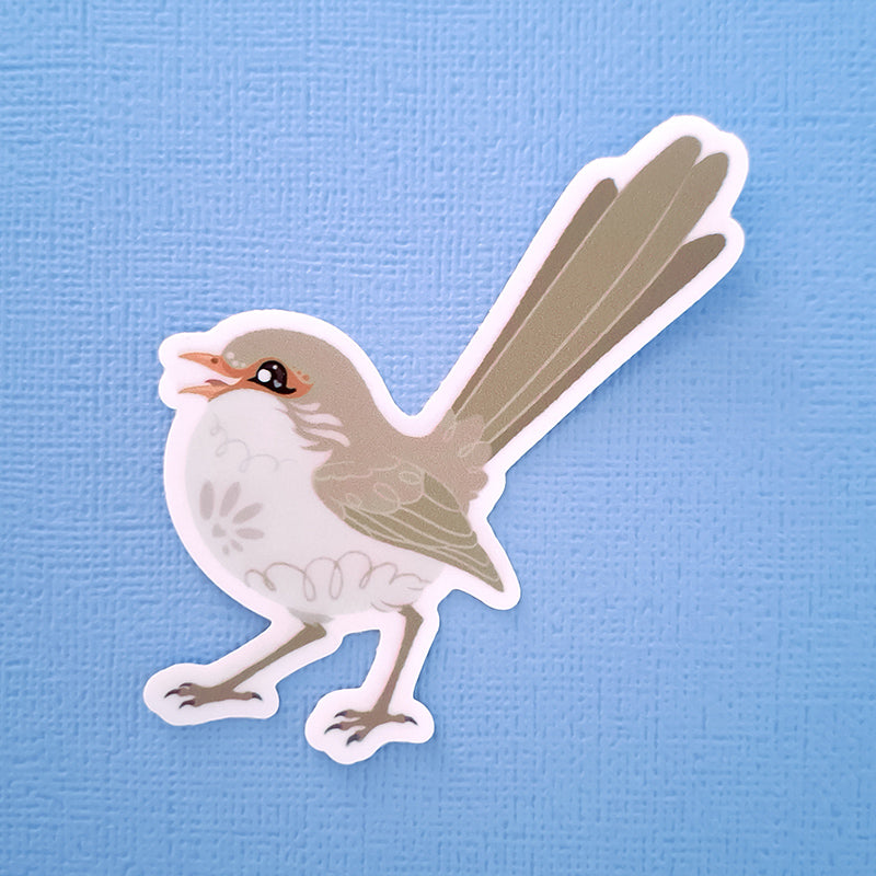 Real photo of a cute sticker of a female Superb Fairywren chirping on a blue canvas textured background.