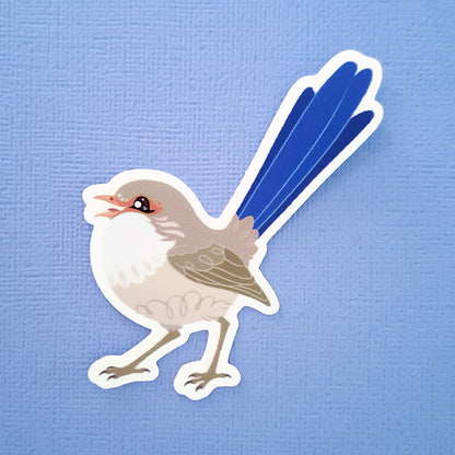 Real photo of a colourful sticker of a female White-winged Fairywren chirping on a blue canvas textured background.