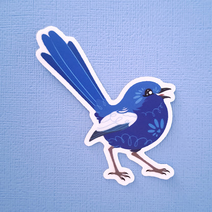 Real photo of a colourful sticker of a male White-winged Fairywren chirping on a blue canvas textured background.