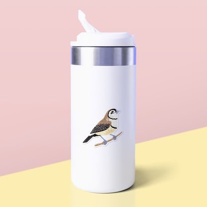 Colourful die-cut sticker of a double-barred owl finch stuck to a white metal drink bottle on a soft yellow table on a soft peach background.
