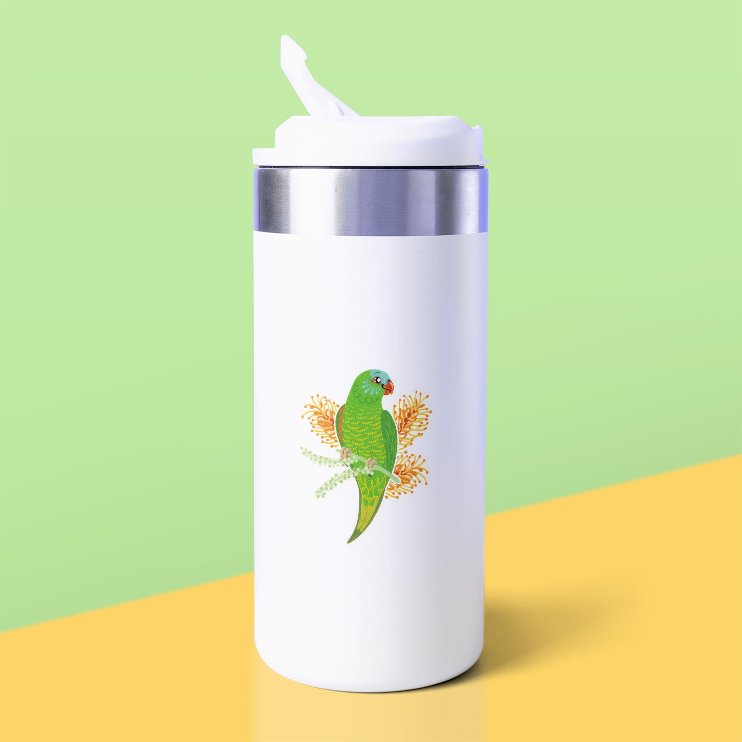A colourful sticker of a scaly-breasted lorikeet with orange grevillea flowers stuck to a white metal drink bottle on a yellow table on a green background.