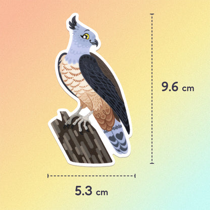 5.3x9.6cm colourful sticker of a pacific baza perched on a tree branch on an orange, yellow and aqua gradient background.