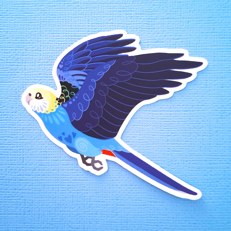 Real photo of a colourful sticker of a Pale-Headed Rosella in flight on a blue canvas textured background.