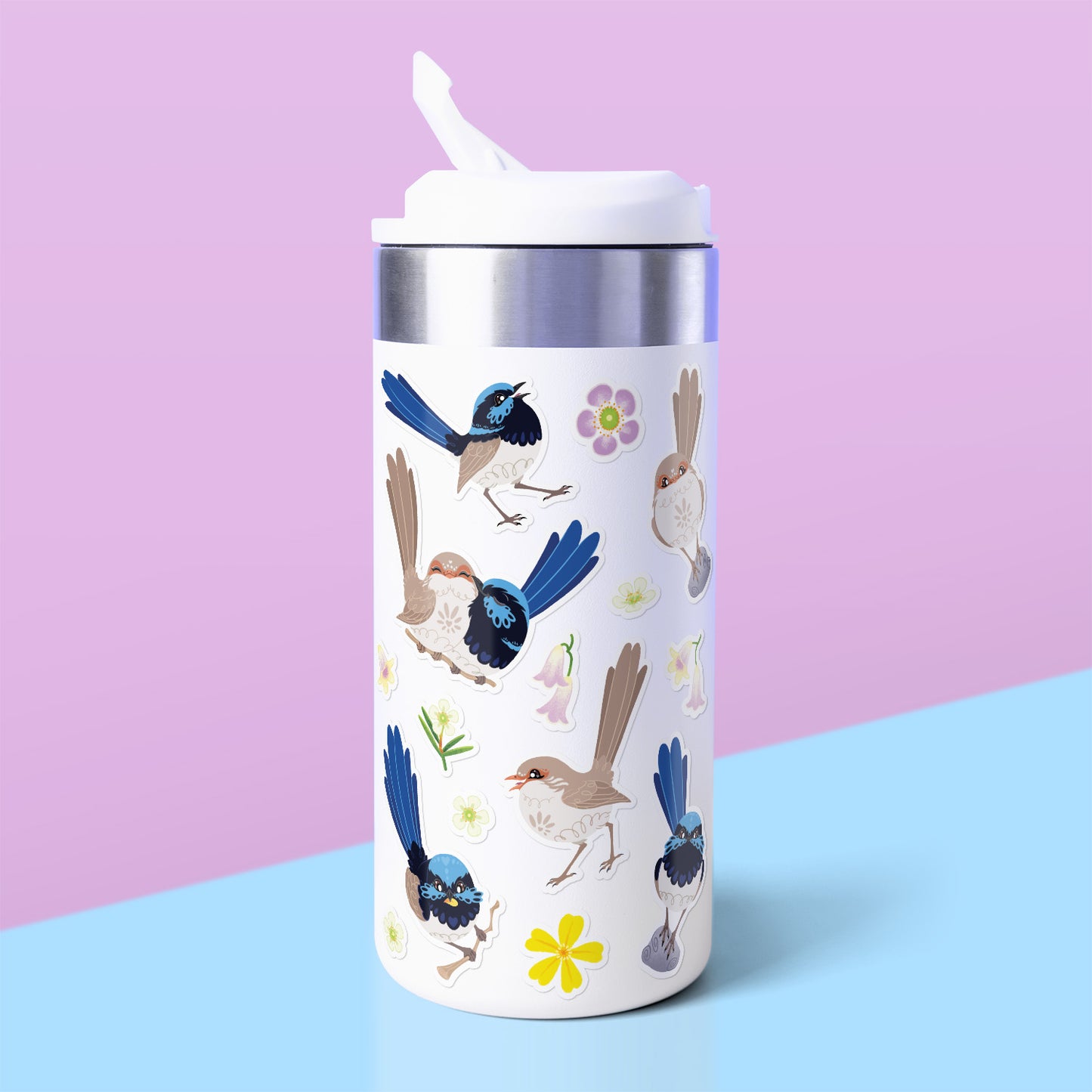 Colourful stickers of male & female Superb Fairywrens and assorted native flowers stuck to a white metal drink bottle on a blue table on a pale lilac background.