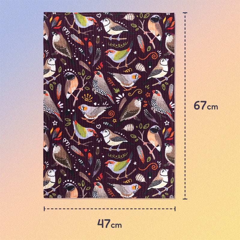 47x67cm tea towel with a burgundy Australian finches pattern sitting flat on a pastel blue, orange and yellow background.