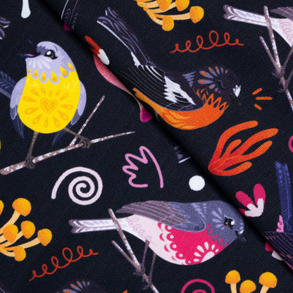 Closeup of a tea towel with a black, pink, orange and yellow Australian robins pattern.