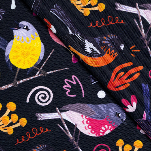 Closeup of a tea towel with a black, pink, orange and yellow Australian robins pattern.