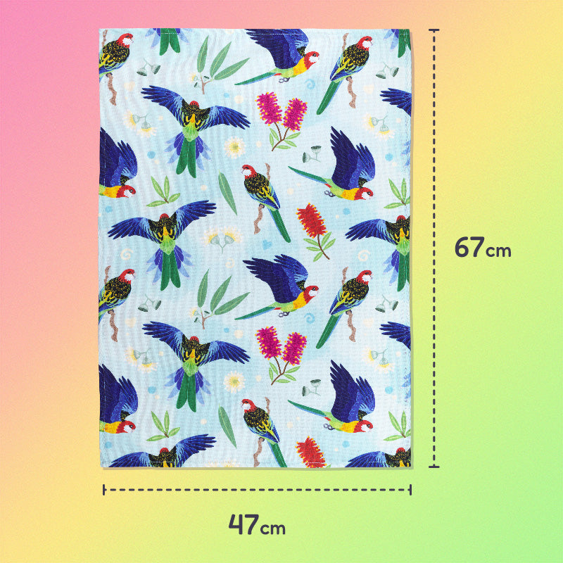 47x67cm tea towel with a rainbow eastern rosellas pattern sitting flat on a pastel pink, yellow and green background.