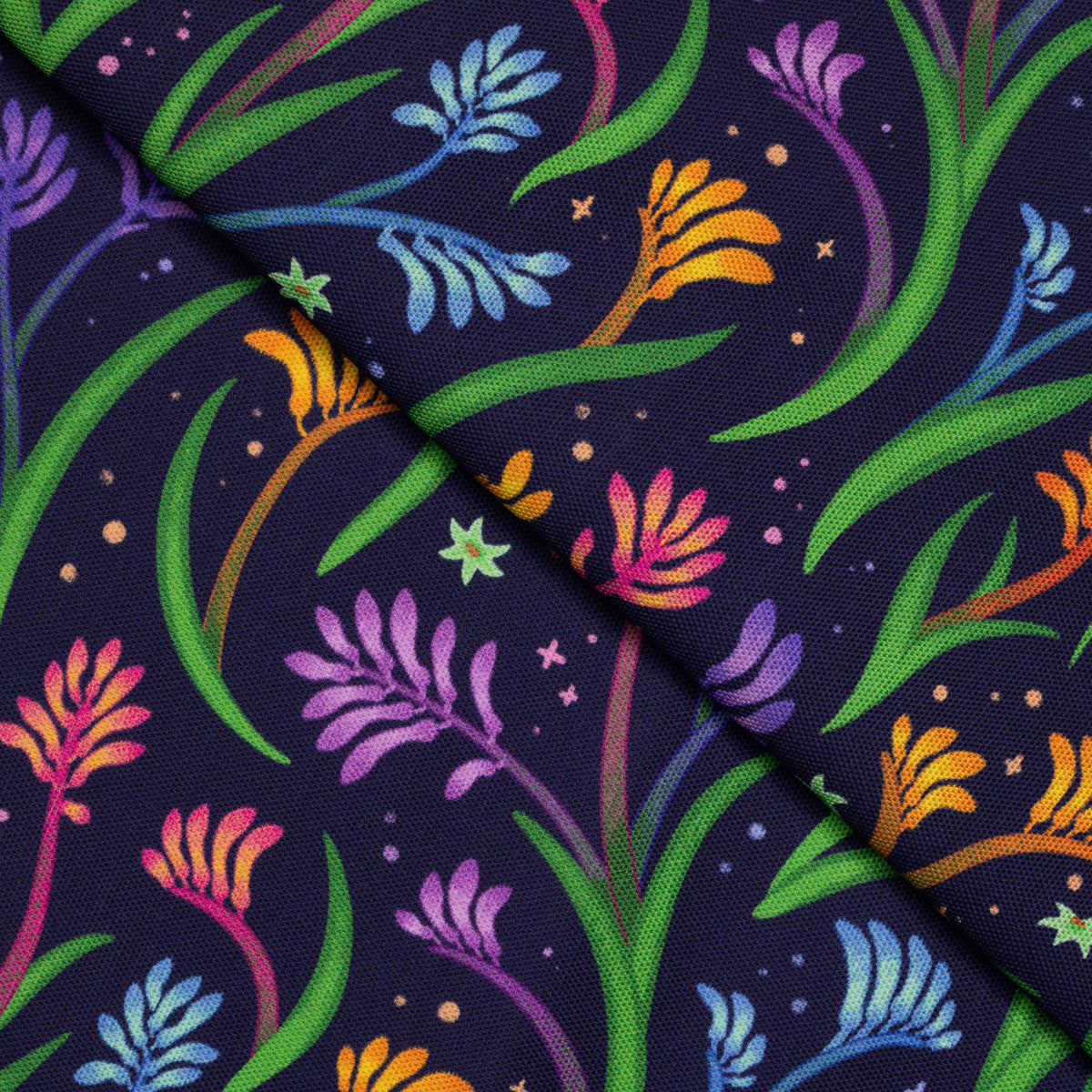 Closeup of a folded tea towel with a rainbow kangaroo paw pattern.