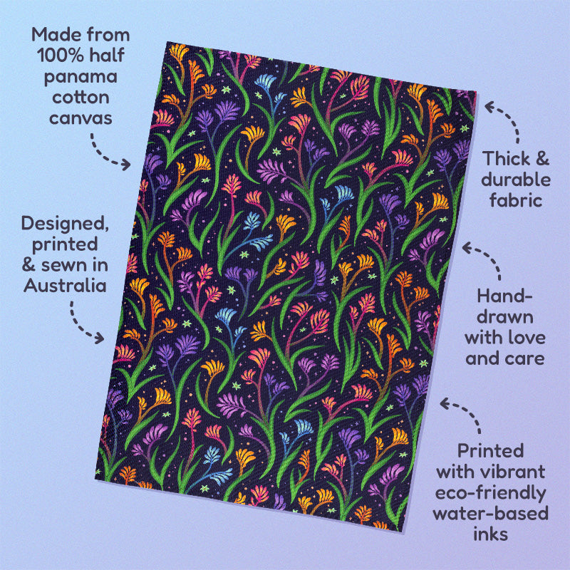 Features & benefits ('Made from 100% half panama cotton canvas, designed, printed & sewn in Australia, thick & durable fabric, hand-drawn with love and care, printed with vibrant eco-friendly water-based inks) surrounding a tea towel with a rainbow kangaroo paw pattern sitting on a pastel blue and purple background.