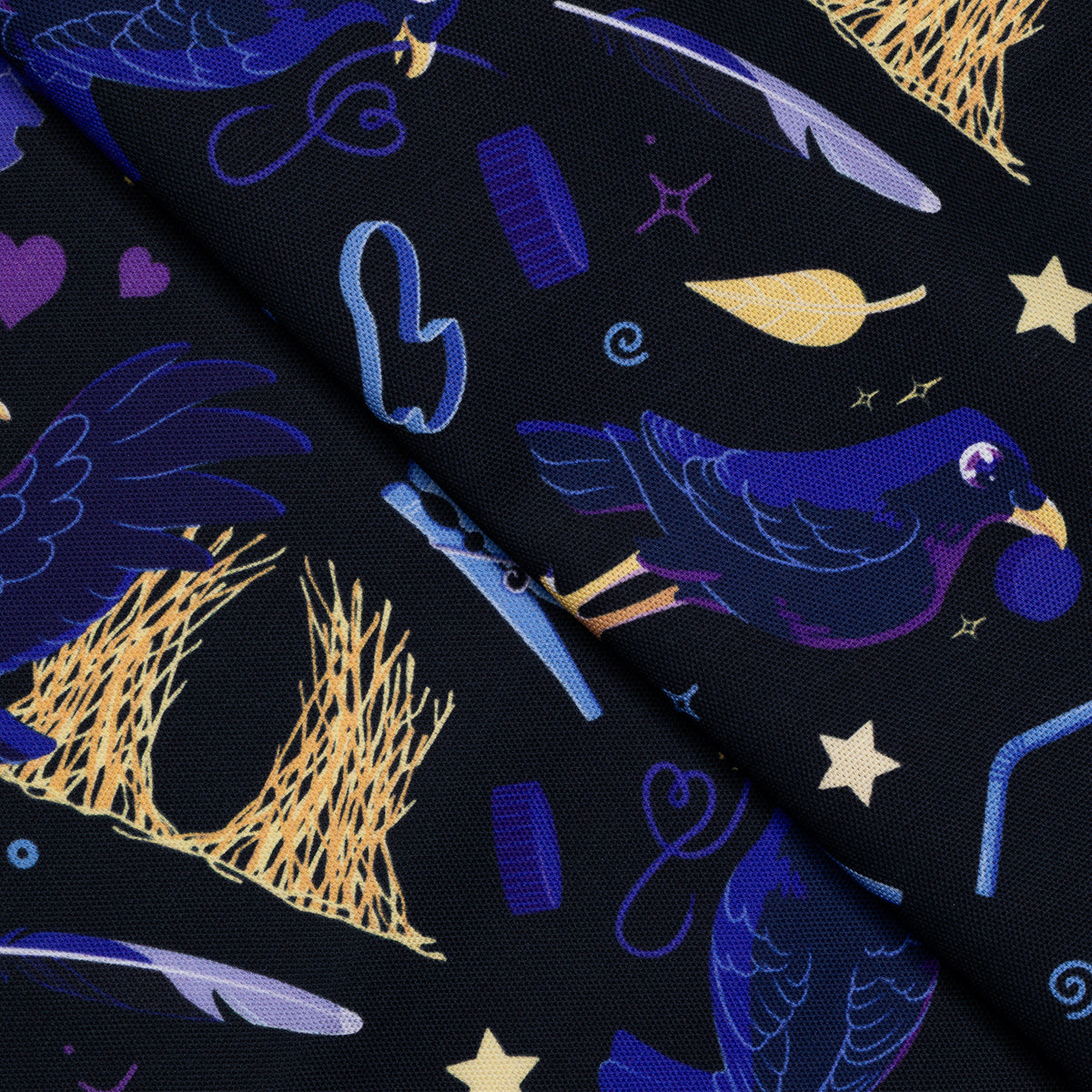 Closeup of a folded tea towel with a black, blue, purple and yellow satin bowerbirds pattern.