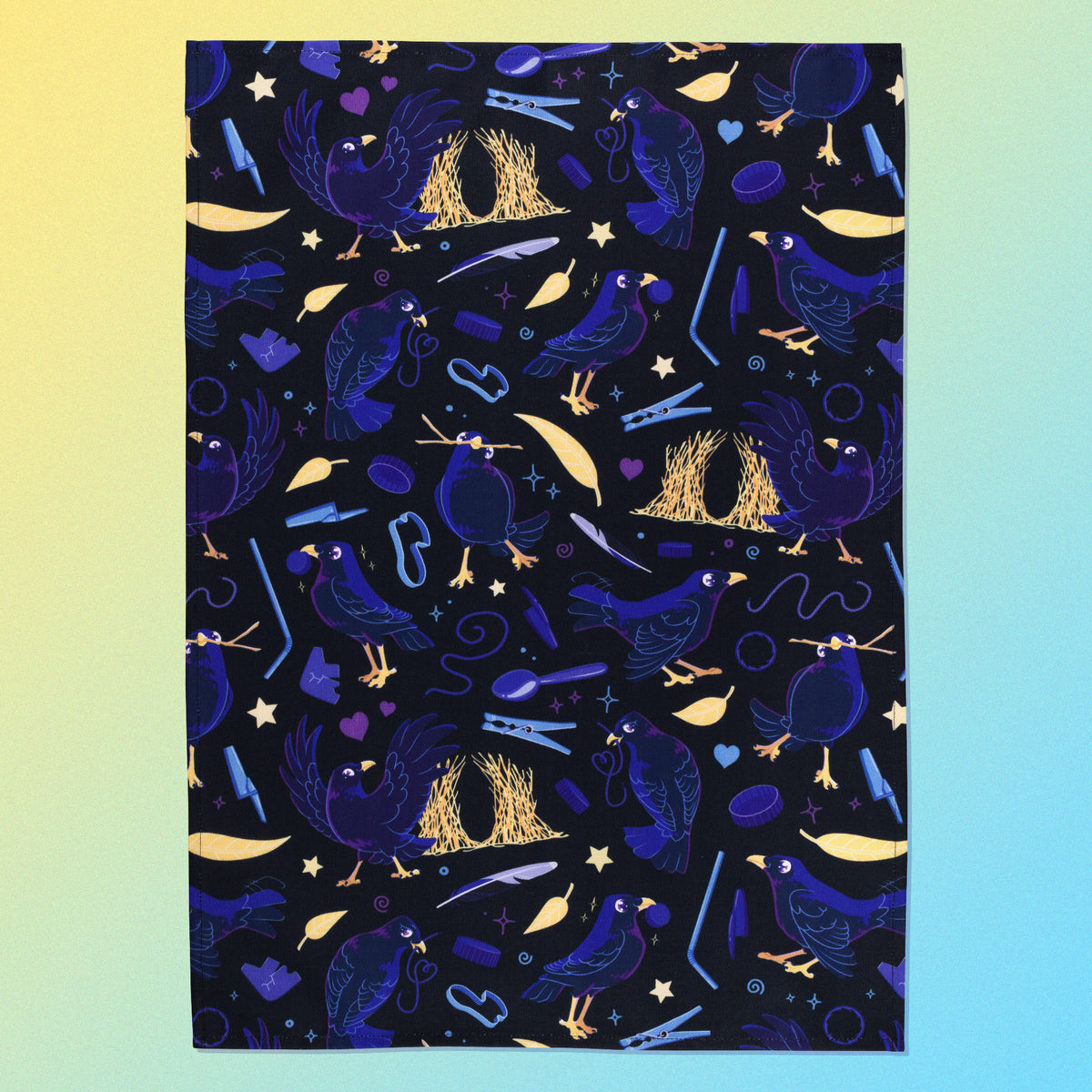 A tea towel with a black, blue, purple and yellow satin bowerbirds pattern sitting flat on a pastel yellow and blue background.