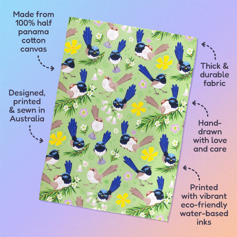 Features & benefits ('Made from 100% half panama cotton canvas, designed, printed & sewn in Australia, thick & durable fabric, hand-drawn with love and care, printed with vibrant eco-friendly water-based inks) surrounding a tea towel with a green, blue, yellow and beige superb fairywrens pattern sitting flat on a pastel blue, pink and apricot background.