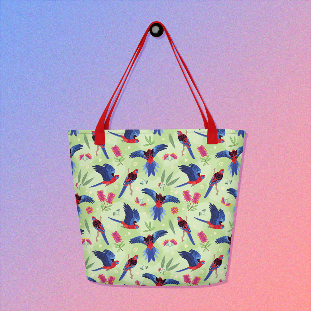 Tote bag with red handles and a crimson rosella parrot pattern on a gradient purple and pink background
