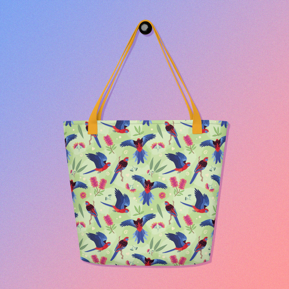 Tote bag with yellow handles and a crimson rosella parrot pattern on a gradient purple and pink background