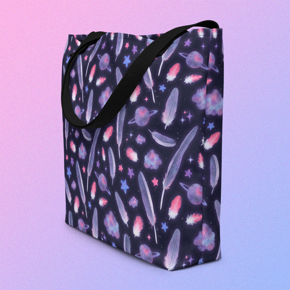 Tote bag with a black strap and galah cockatoo feather and galaxy-themed pattern on an angle on a gradient purple background