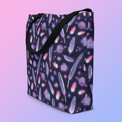 Tote bag with a black strap and galah cockatoo feather and galaxy-themed pattern on an angle on a gradient purple background