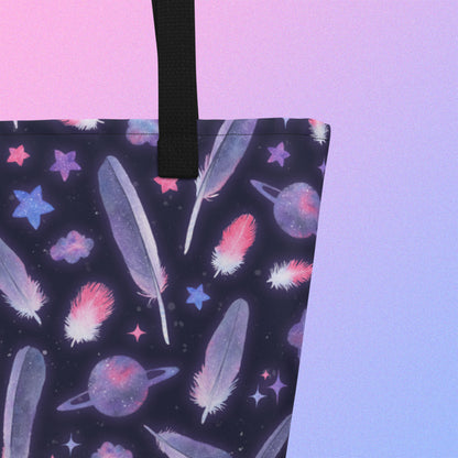 Close up of a tote bag with a black strap and galah cockatoo feather and galaxy-themed pattern on a gradient purple background