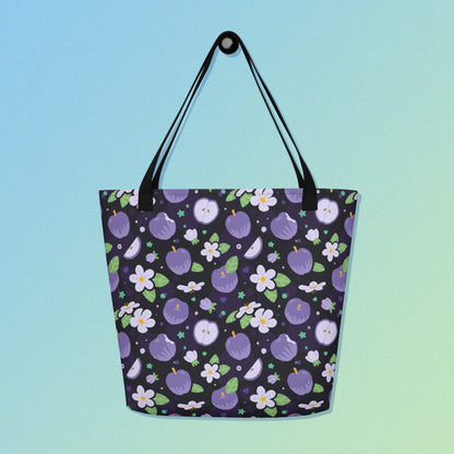 Tote bag with a black strap and purple apple and flower pattern on a gradient blue and green background