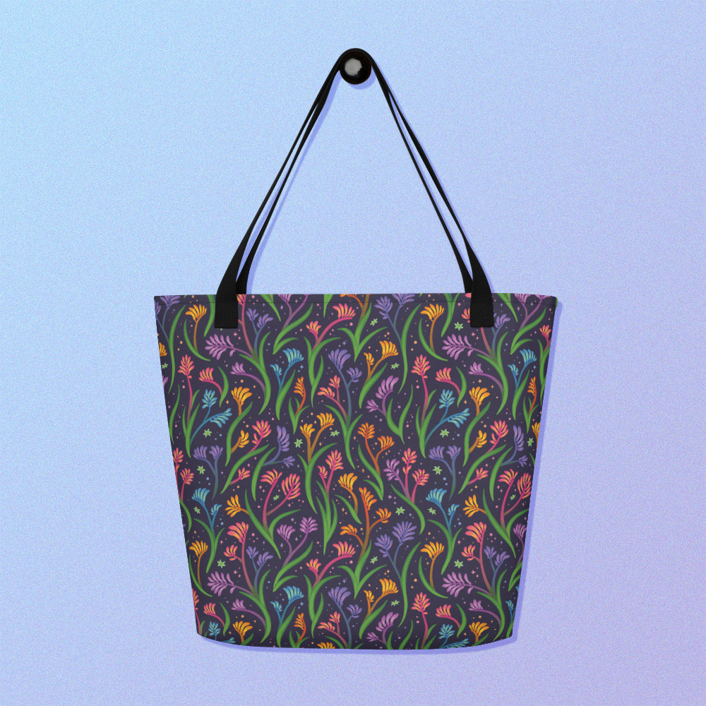 Tote bag with a black strap and a floral rainbow kangaroo paw pattern on a gradient blue and purple background.