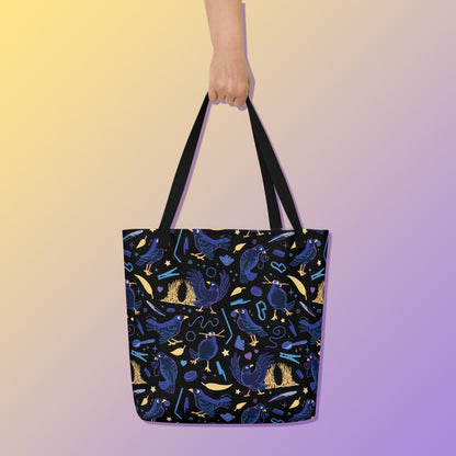 Hand holding a tote bag with black handles and a black/blue/yellow satin bowerbird pattern pattern on a yellow and purple gradient background.