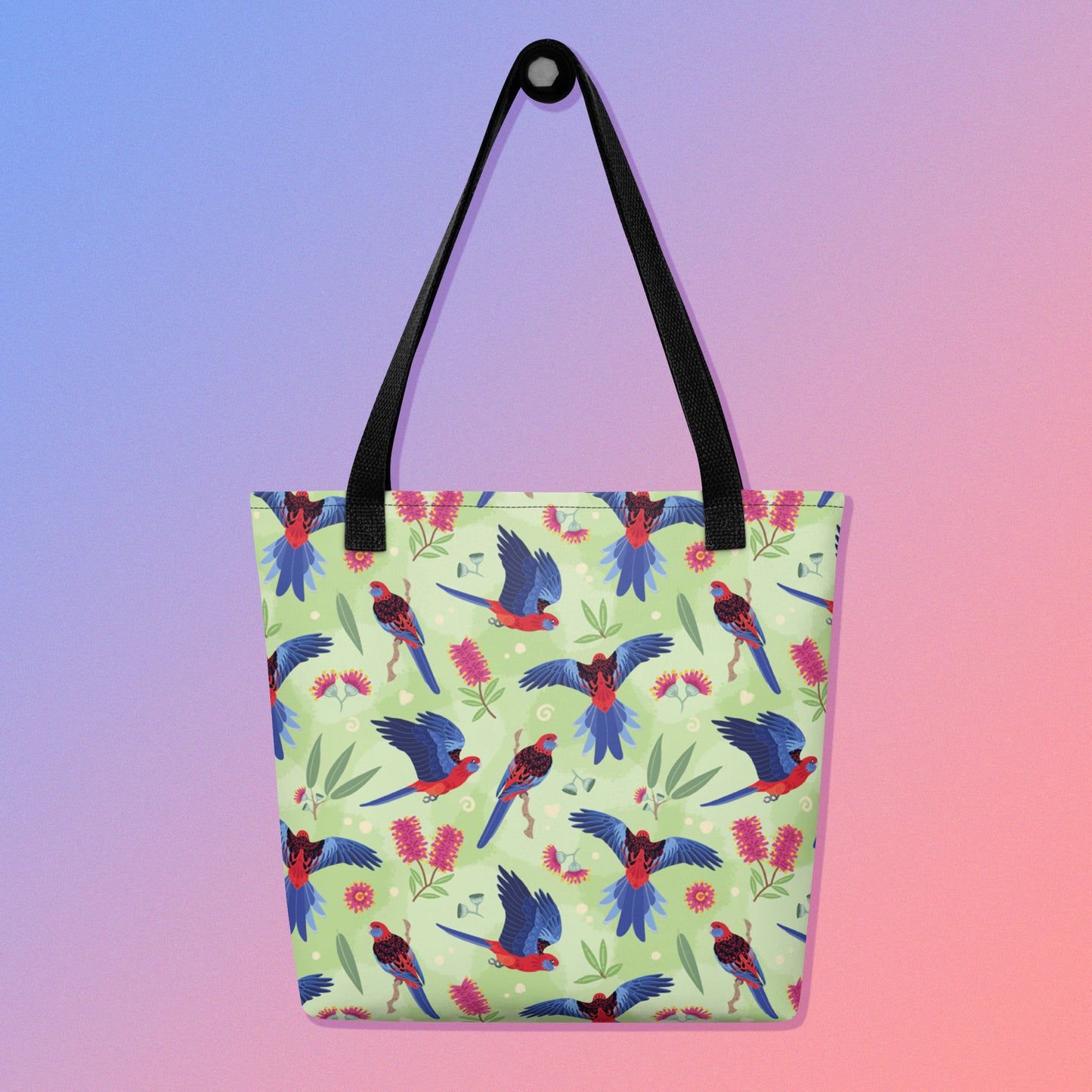 Tote bag with black handles and a crimson rosella parrot pattern on a gradient purple and pink background