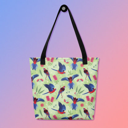 Tote bag with black handles and a crimson rosella parrot pattern on a gradient purple and pink background