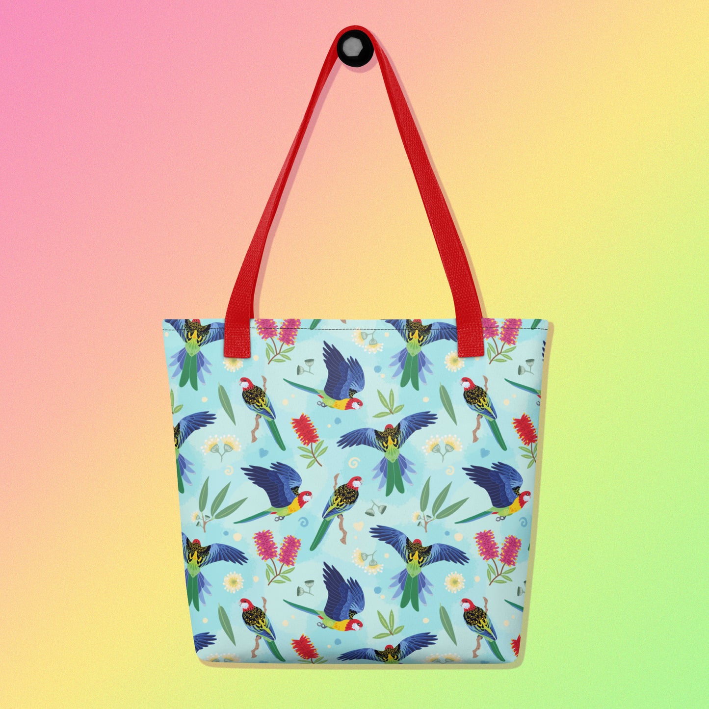 Tote bag with red handles and an eastern rosella parrot pattern on a gradient pink, yellow and green background