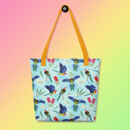 Tote bag with yellow handles and an eastern rosella parrot pattern on a gradient pink, yellow and green background
