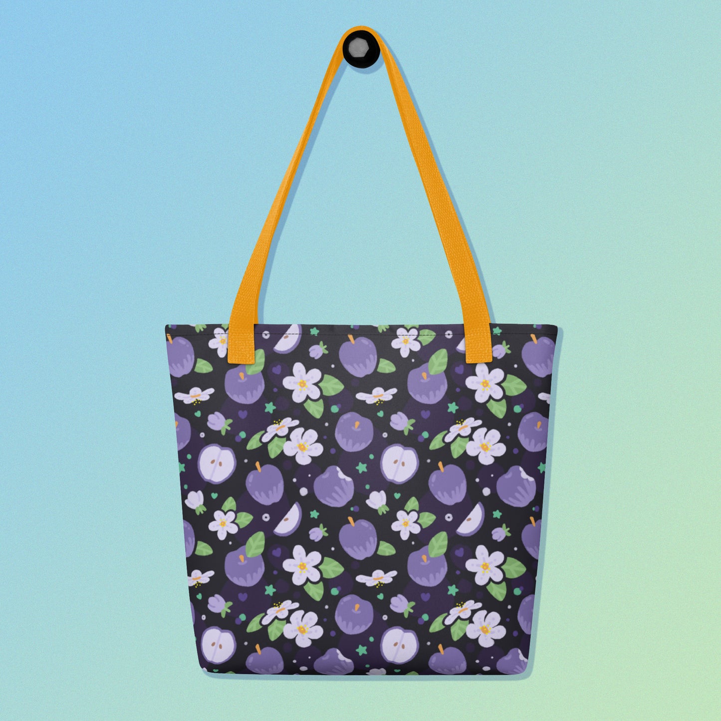Tote bag with a yellow strap and a purple apple and flower pattern on a gradient blue and green background
