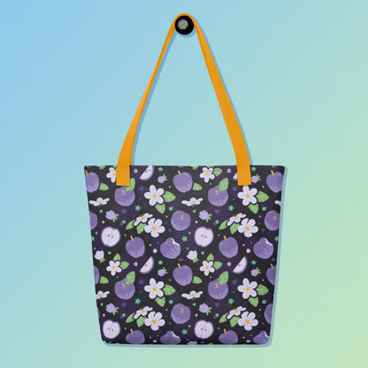 Tote bag with a yellow strap and a purple apple and flower pattern on a gradient blue and green background