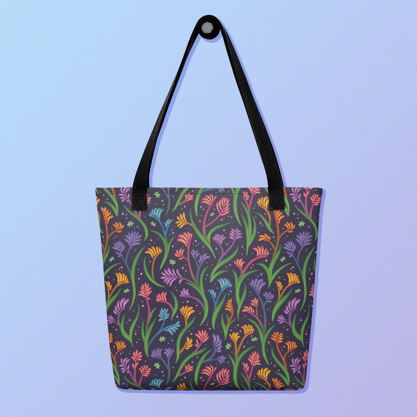 Tote bag with a black strap and a floral rainbow kangaroo paw pattern on a gradient blue and purple background.
