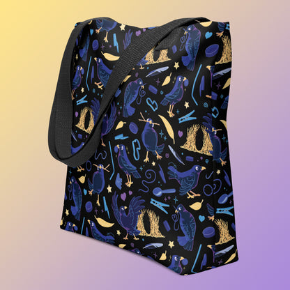 Tote bag with black handles and a black/blue/yellow satin bowerbird pattern pattern on an angle on a yellow and purple gradient background