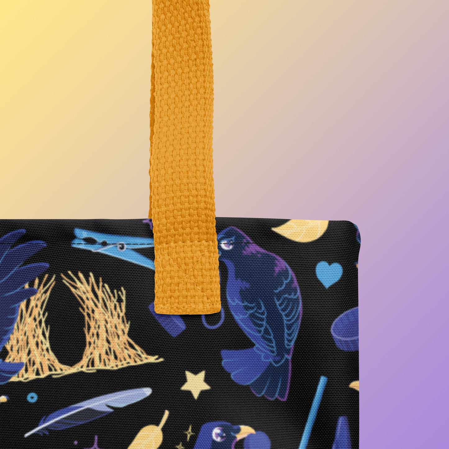 Close up of a tote bag with yellow handles and a black/blue/yellow satin bowerbird pattern pattern on a yellow and purple gradient background
